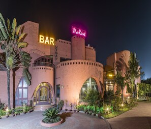 Een hotel met een opvallende bar en een neonbord voor 'Utan Resort'.