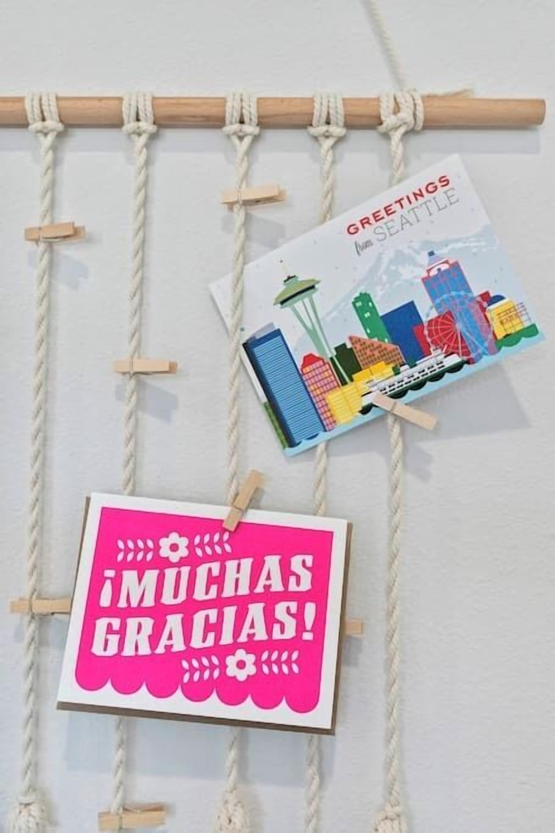 A wall with a wooden rope hanging from the ceiling, holding cards and a sign.