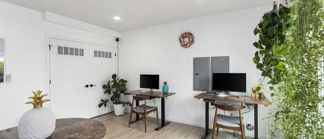 A modern living room with two wooden tables, a large potted plant, and a decorative pineapple on one table.