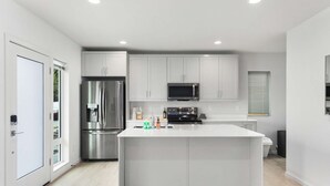 Una cocina moderna con una isla central, electrodomésticos de acero inoxidable y armarios blancos.