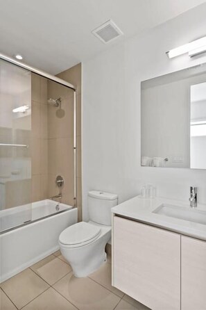 Une salle de bain moderne avec une douche à parois de verre, des toilettes et un meuble-lavabo avec un miroir.