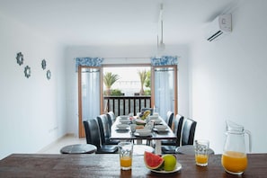 A dining area with a table set for four, chairs, a fruit bowl, and a pitcher of juice.