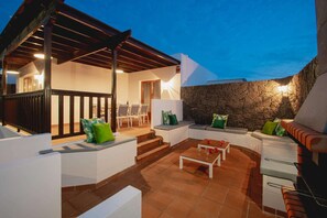 An outdoor patio with a stone wall, seating area, and a covered section.