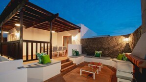 An outdoor patio area with a stone wall, white furniture, and a pergola structure. - 6 Bed Holiday Villa | Heated Pool | Hot Tub | Beach & Waterparks | Playa Blanca (Playa Blanca)