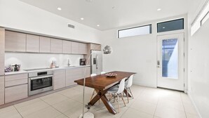 Een moderne keuken met een houten eettafel, witte stoelen en een inbouwoven.