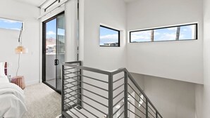 Een modern interieur met een trap, een bed en een uitzicht door een glazen deur.
