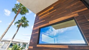 Een modern gebouw met een groot raam dat de lucht en palmbomen weerspiegelt.
