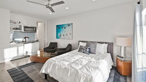 Une chambre d’hôtel moderne équipée d’un lit, d’un bureau, d’une chaise, d’un four à micro-ondes et d’un ventilateur de plafond.