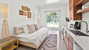 Een moderne slaapkamer met een bed, nachtkastje en uitzicht op een zwembad door een glazen deur.