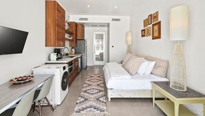 Een compacte hotelkamer met een kitchenette, een bed, een bureau en een televisie.