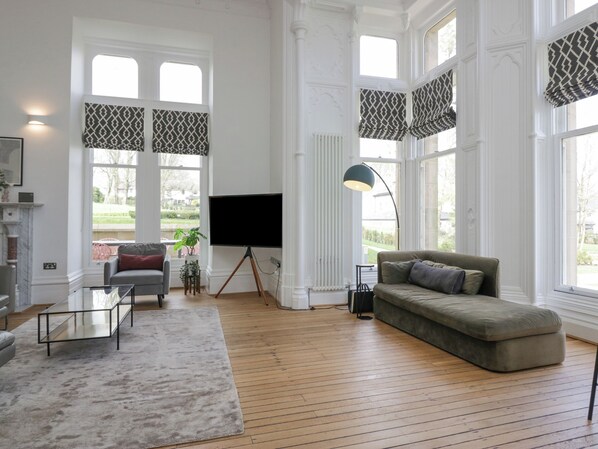 A spacious living room with a large window, a fireplace, a sofa, and a TV.