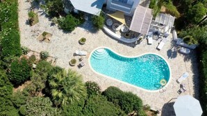 An aerial view of a property with a swimming pool surrounded by lounge chairs and a small deck area. - Riviera paradise villa with private pool (Amorgos)