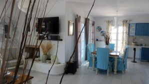 A dining area with a table and chairs, a television mounted on the wall, and a kitchen area with cabinets and a countertop. - Riviera paradise villa with private pool (Amorgos)