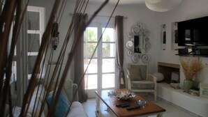 A living room with a sofa, a coffee table, a TV, and a fireplace. - Riviera paradise villa with private pool (Amorgos)