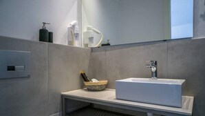 Une salle de bain moderne avec un lavabo rectangulaire, un miroir et une étagère contenant des articles de toilette.