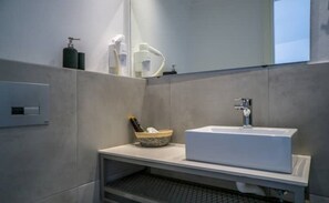 Een moderne badkamer met een rechthoekig wastafel, een spiegel en een plank met toiletartikelen.