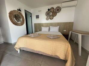 Een hotelkamer met een bed, een wandairconditioner en een ronde decoratie aan de muur.
