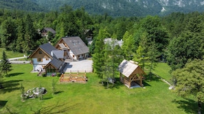 A cluster of wooden houses surrounded by lush greenery and mountains. - ALPIK Chalets - Bohinj - A5 - Duplex Three-Bedroom App - Balcony - Fireplace (Ukanc)