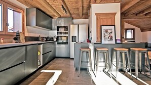 Una cocina moderna con vigas de madera, electrodomésticos de acero inoxidable y taburetes de bar.