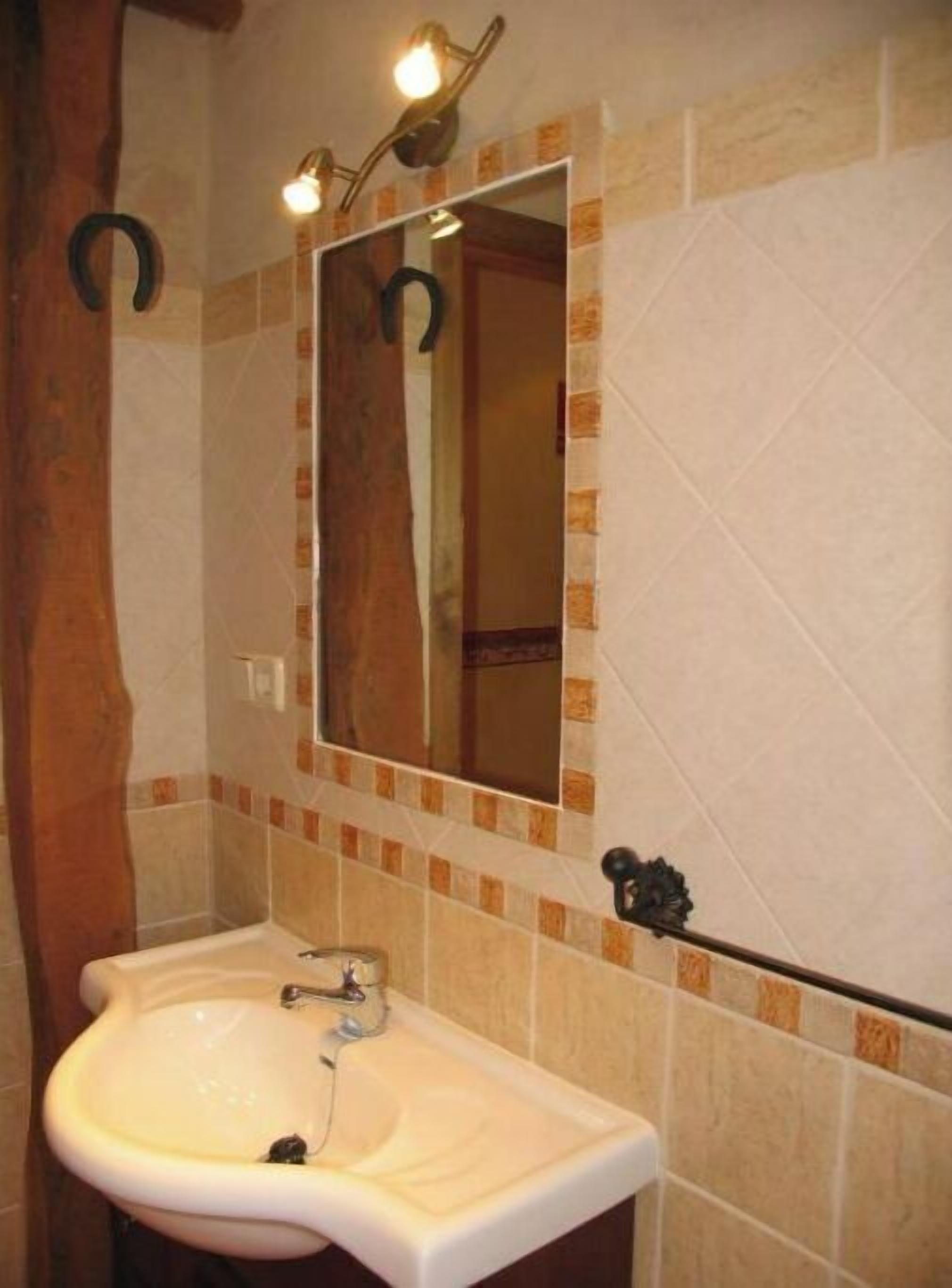 Un baño con lavamanos, espejo y paredes con azulejos.