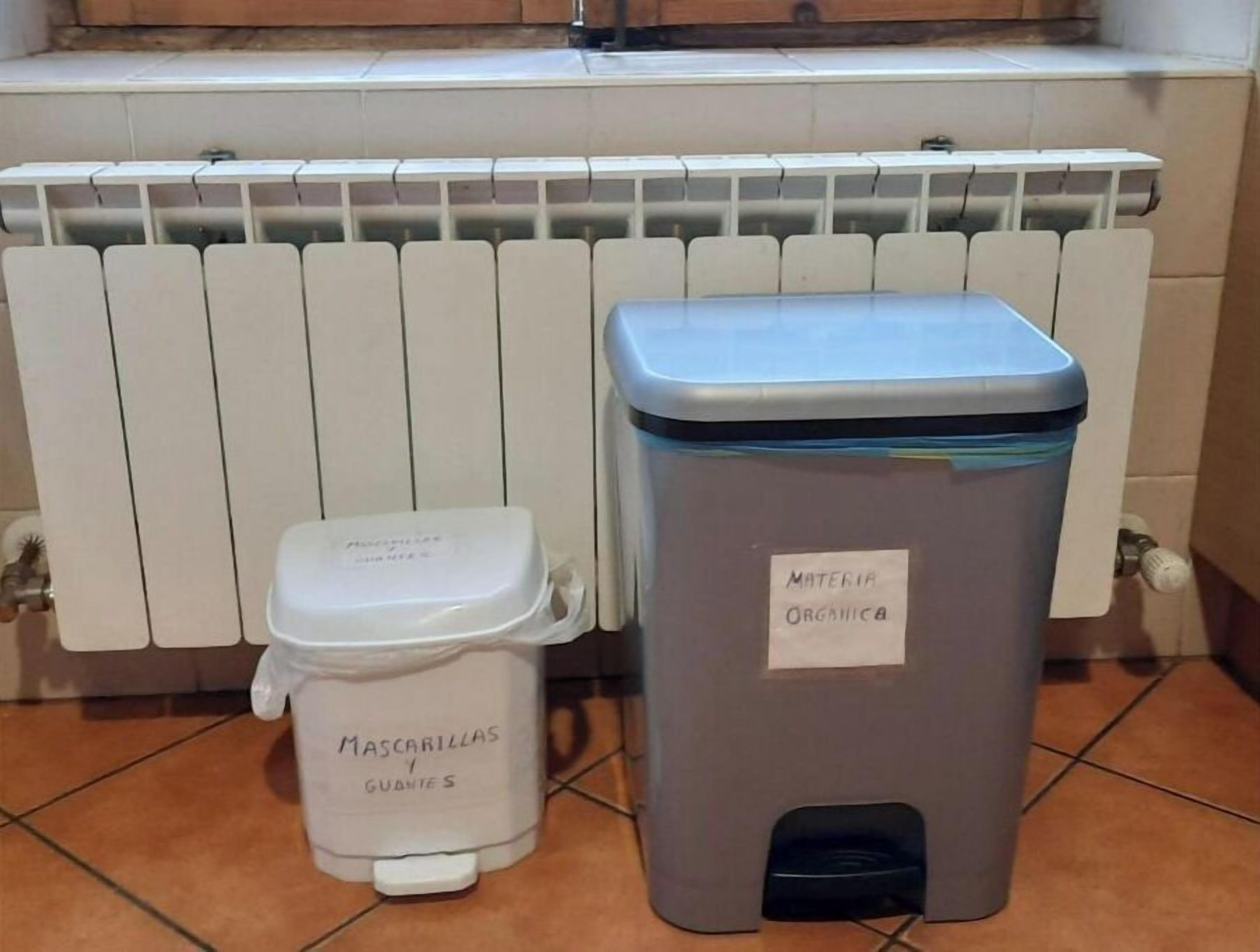 Two waste bins labeled "Mascarillas y Guantes" and "MATERIA ORGANICA" in a tiled bathroom.