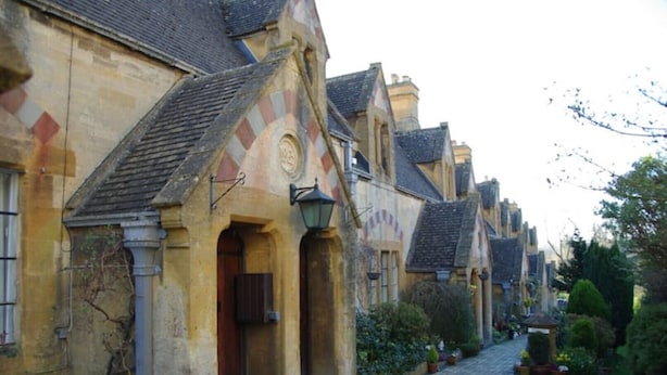 Une rangée de bâtiments traditionnels en pierre, dotés d’entrées en arc de cercle et bordée d’une rue pavée.