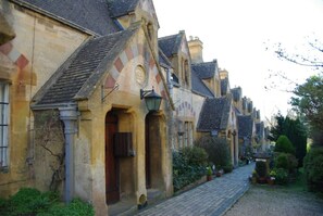 A row of traditional stone buildings with arched doorways and a cobblestone street.