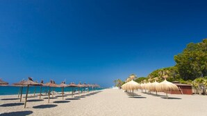 Een strand met rieten parasols en een helderblauwe lucht.