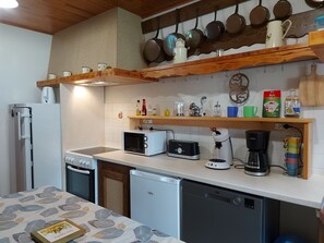 A compact kitchen with a refrigerator, microwave, toaster, coffee maker, and dishwasher.