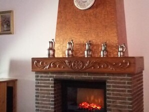 Een metsen haard met decoratieve bovenplaat en vier metalen vazen.
