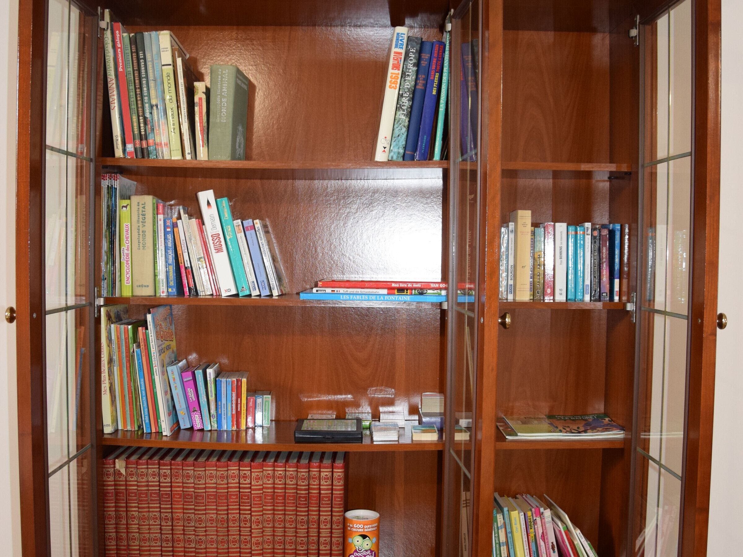 Een houten boekenplank vol boeken en een blik.