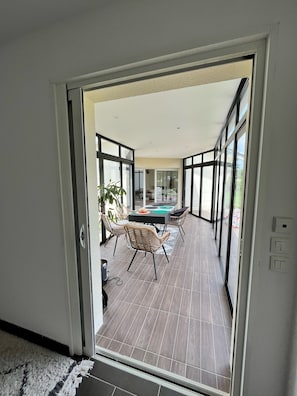 A modern interior with a dining area featuring a table and chairs, a large window, and a view of the outdoors.