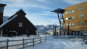 A snow-covered path leading to a wooden building with a sloped roof, adjacent to a modern building with large windows and a metal structure. - Great Rates, Hot Tub, Tranquil Views & Location (Park City)