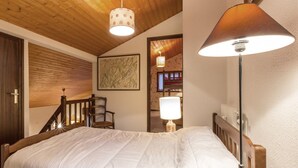 A bedroom with a wooden bed, a chair, a map on the wall, and a staircase. - Charming 3-room with mezzanine for 6 pers, south balcony and parking in La Clusaz (La Clusaz)