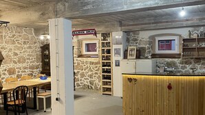A rustic interior with a stone wall, a wooden dining table, and a bar area. - Cozy house in the village (Siveric)
