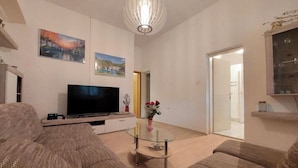 A living room with a flat-screen TV, two sofas, a glass coffee table, and a chandelier. - Cozy house in the village (Siveric)