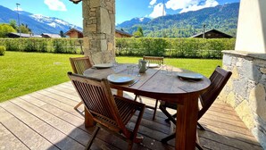 A wooden deck with a table set for four, surrounded by stone pillars, overlooking a mountainous landscape. - T2 Apartment with Large Terrace and Pets Allowed (Samoëns)