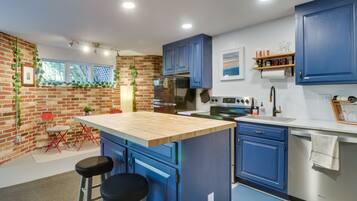 A modern kitchen with blue cabinets, a wooden island, and a brick wall.