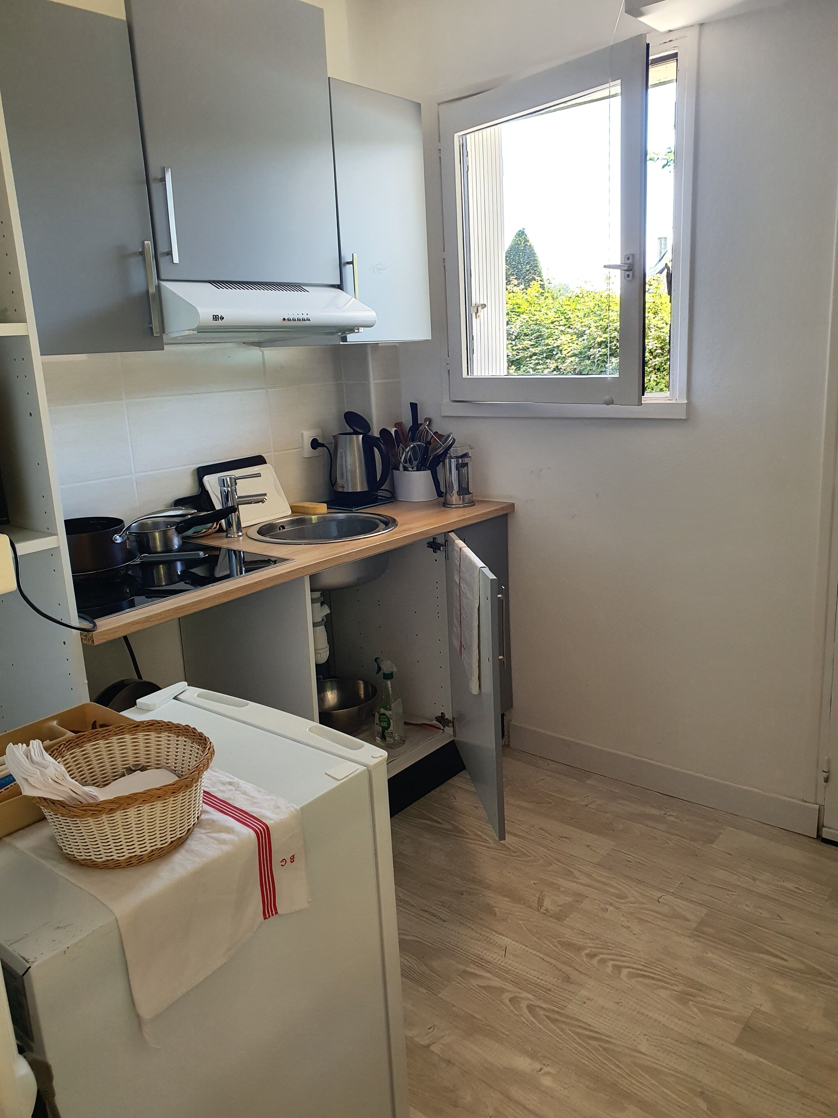 A compact kitchen with a gas stove, a sink, and a window providing a view of greenery outside.