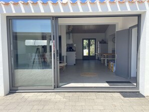 Un intérieur moderne comprenant une cuisine, un coin repas et une porte-fenêtre coulissante donnant sur un espace extérieur.