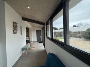 Un couloir moderne avec un banc, une porte et une fenêtre donnant sur une serre.