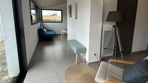 A modern living room with a sofa, a bench, a lamp, and a view of the outside.