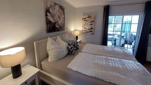 Hotellihuone, jossa on sänky, yöpöytä, lamppu ja ikkuna, josta on näkymä.
