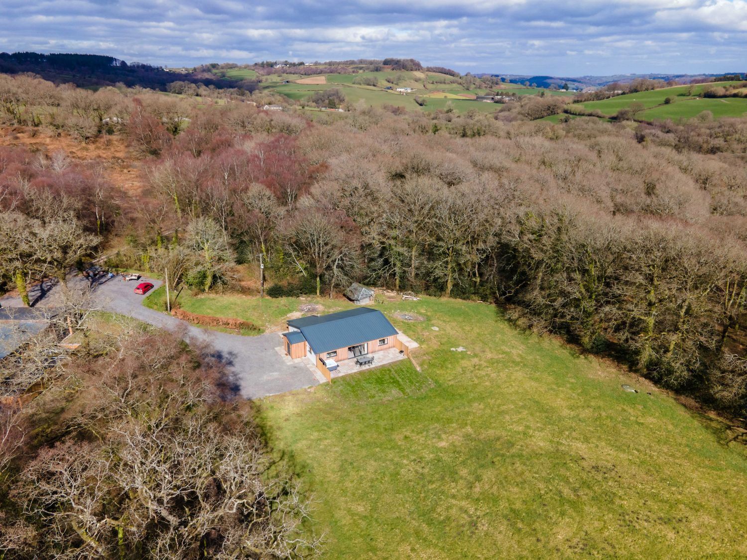 An aerial view of a rural property with a main building, a parking area, and surrounding fields.