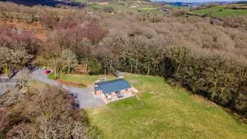 An aerial view of a rural property with a main building, a parking area, and surrounding fields.