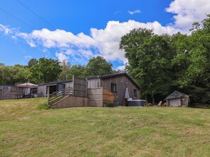 A rustic wooden barn with a covered porch and a small shed.