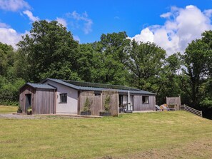 Een rustieke hut met een metalen dak, houten wanden en een veranda met buitenmeubels.