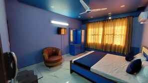 A bedroom with a bed, a chair, a ceiling fan, and a window with curtains. - Guest House Inn karachi (Karachi)