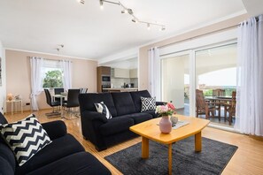 A modern living room with a black sofa, wooden coffee table, and a dining area with a table and chairs. - Villa Elisa with pool in Istria (Rojci)