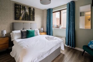 A bedroom with a large bed, a nightstand, a dresser, a window with curtains, and a wall-mounted star decoration.